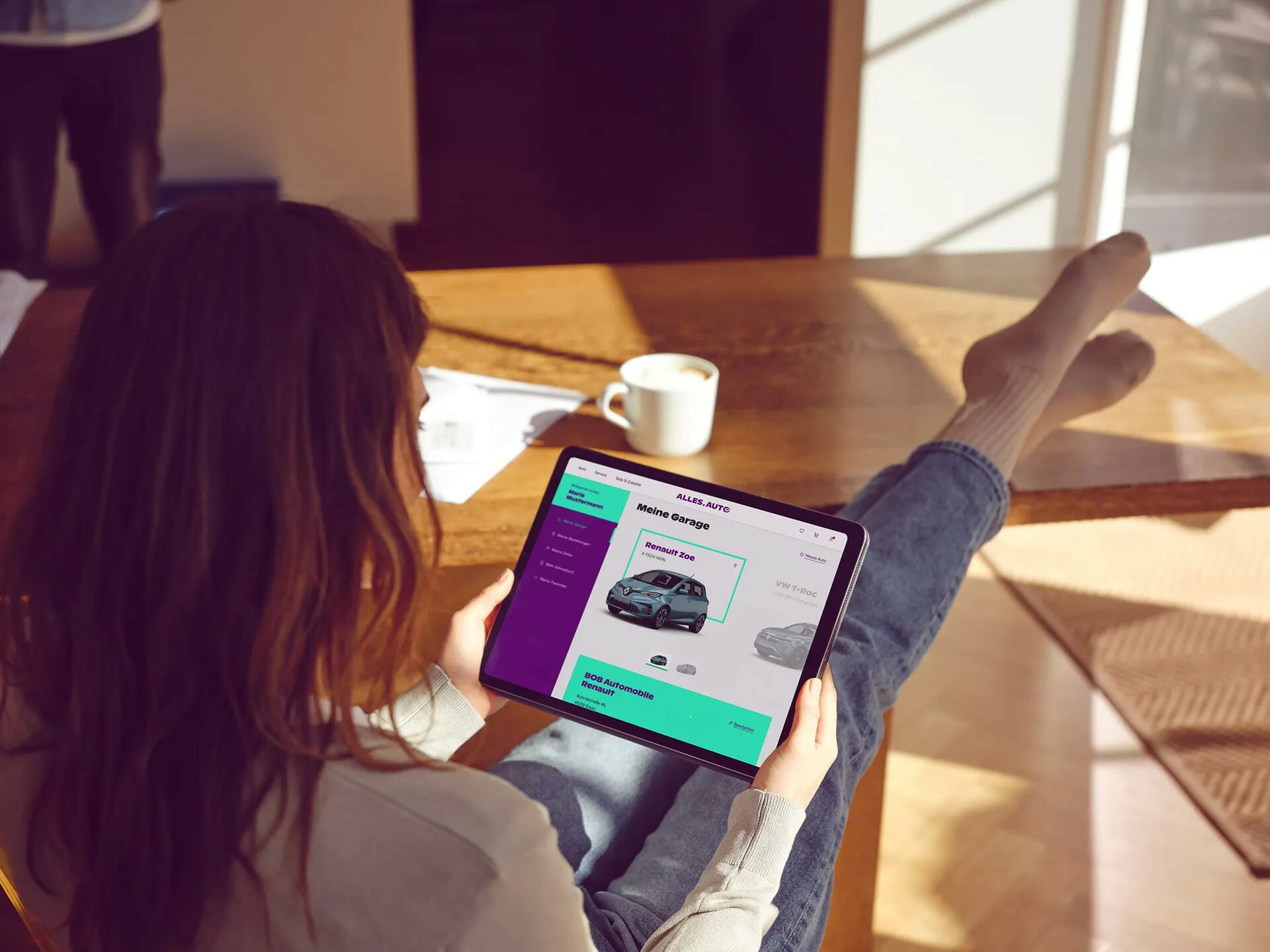 Person sitting at a table with feet up, viewing a car sales app on a tablet, perhaps preparing for the upcoming automotiveIT Kongress.