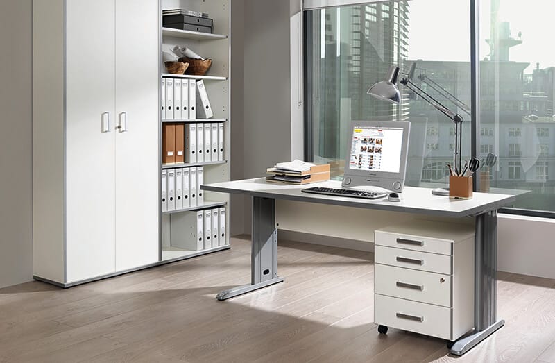 Modern office with a large window, desk featuring a computer, desk lamp, and office supplies, and a filing cabinet. Shelving unit with folders and storage boxes is to the left. Ideal for B2B procurement needs, equipped by Certeo for both functionality and style.