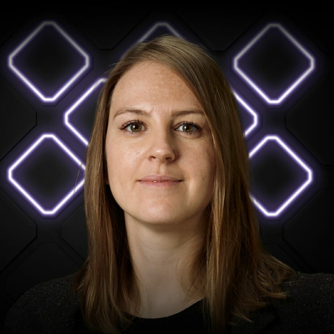 A woman with long hair stands in front of a dark background illuminated by geometric, glowing shapes, capturing the innovative spirit of Spryker EXCITE 2022.