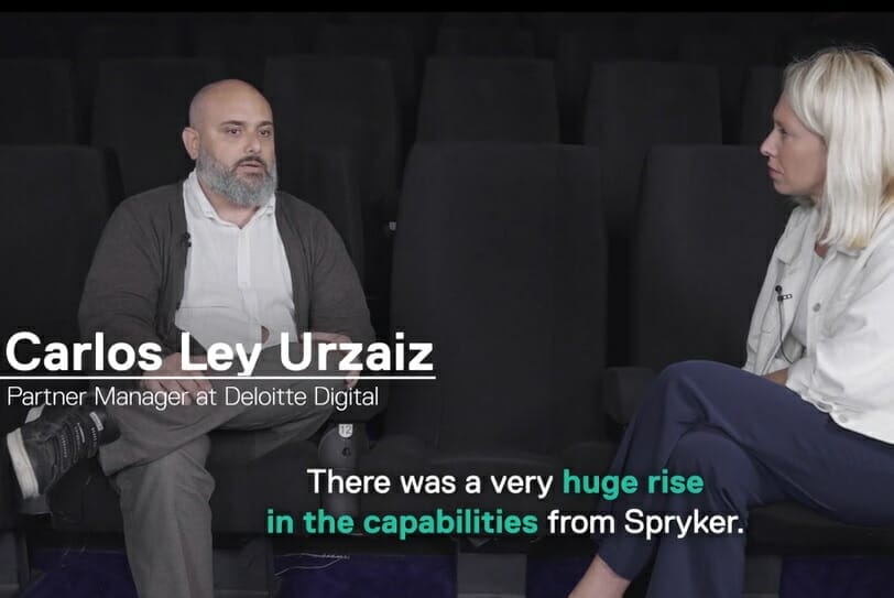 Carlos Ley Urzaiz, Partner Manager at Deloitte Digital, sits in a theater discussing a significant increase in Spryker's capabilities with a woman, giving her an overview of how their partners are integral to this growth.