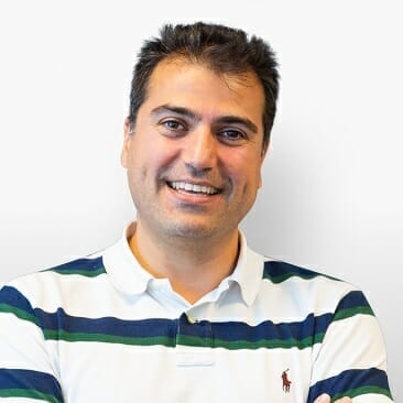 A man with short dark hair, wearing a white and green striped polo shirt, smiling with arms crossed against a plain background—radiating the confidence of an Oracle Commerce expert.