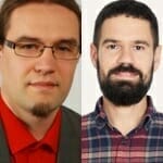 Two men side by side. The man on the left wears glasses, a suit, and a red shirt that seems to EXCITE with vibrance. The man on the right has a beard and is dressed in a plaid shirt.