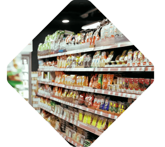 A grocery store aisle containing various packaged snacks and food products, neatly arranged on shelves, offers a convenient option for both individual shoppers and those looking to buy in wholesale.