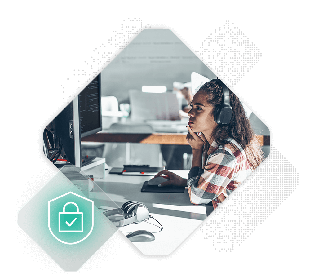 A person with long hair is sitting at a desk with computer monitors, wearing headphones and a plaid shirt, appearing focused. In the foreground, there is a graphic of a green shield with a padlock and checkmark, symbolizing security.